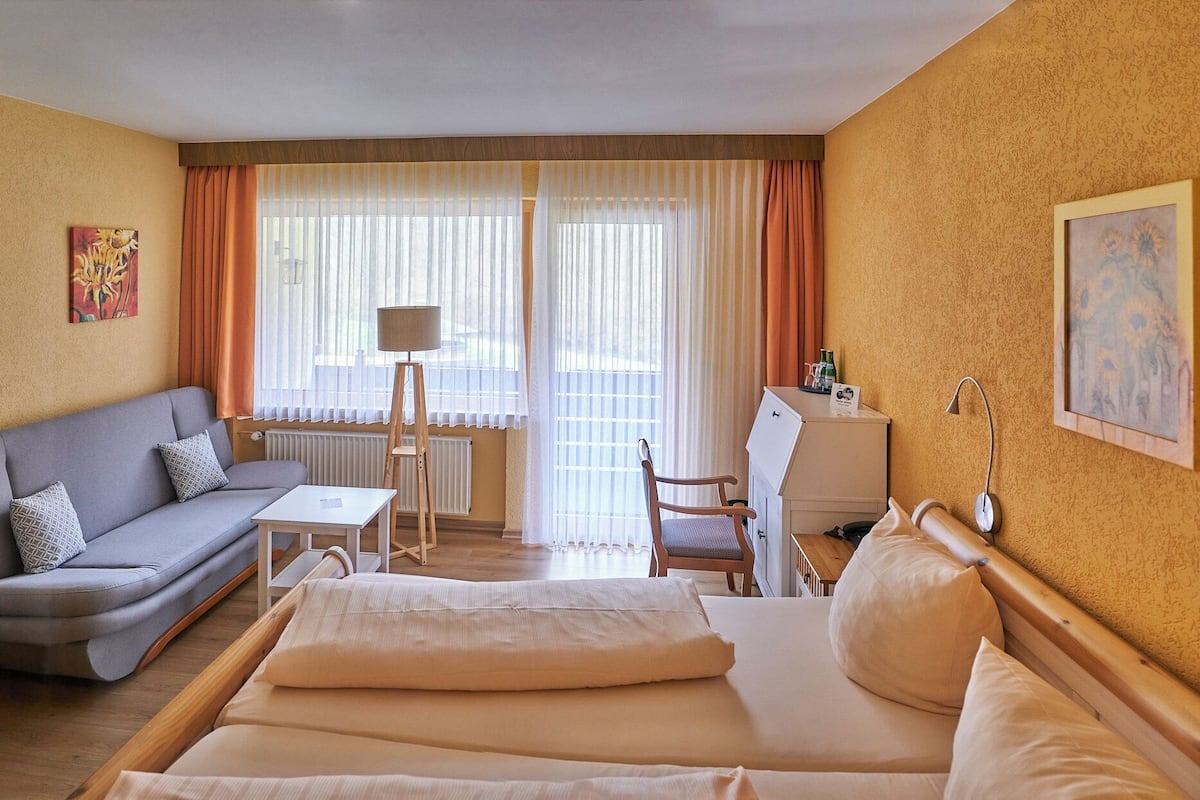 A hotel room with a bed, a sofa, a desk, and a chair.