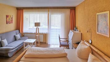 A hotel room with a bed, a sofa, a desk, and a chair.