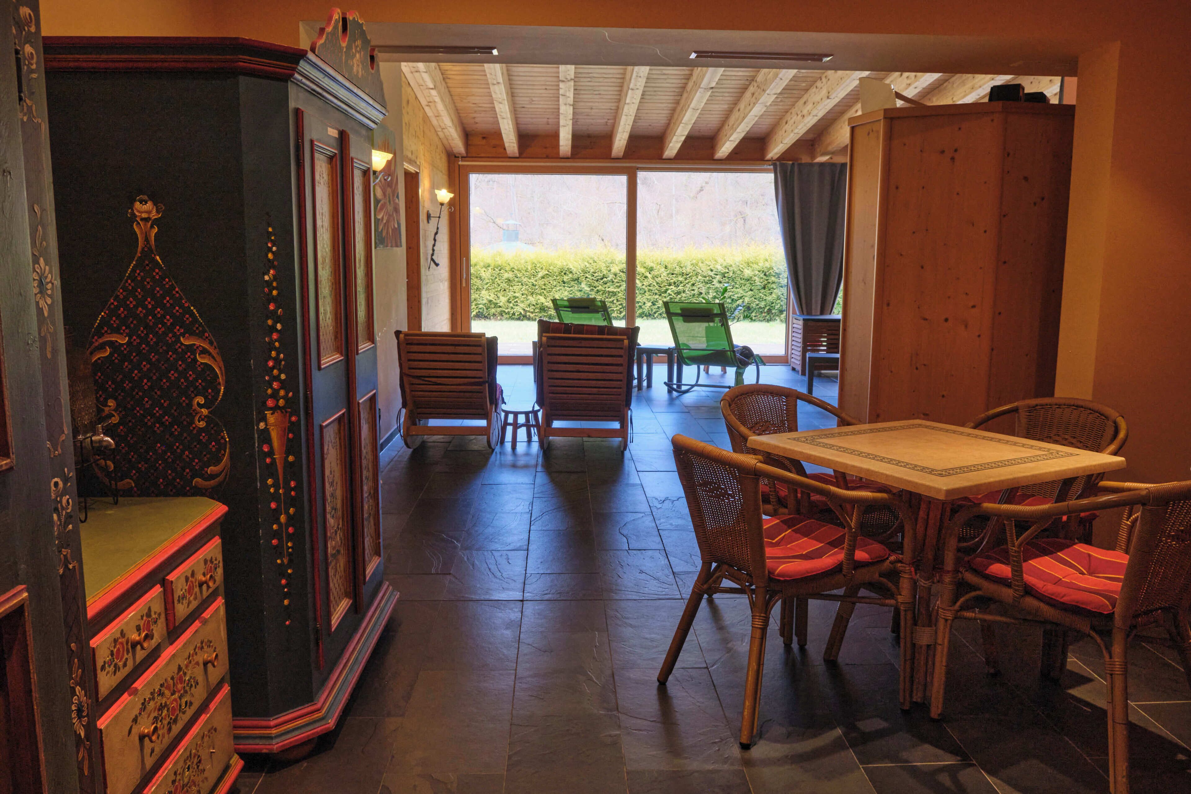A room with a wooden table and chairs, a cabinet, and a view of the outdoors.