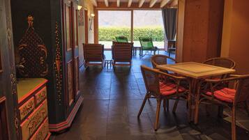 Una habitación con una mesa y sillas de madera, un armario y vistas al exterior.
