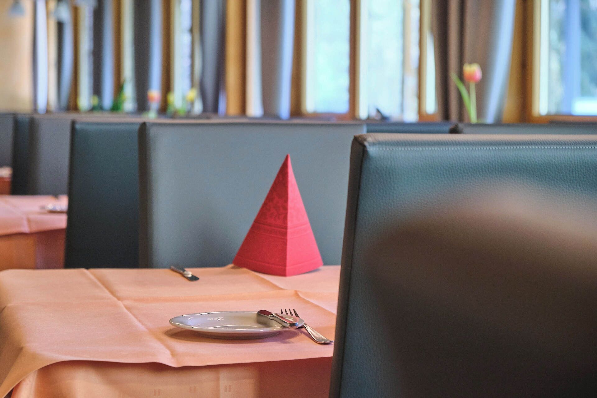 Ein Restaurantambiente mit einem gedecktem Tisch, inklusive Teller, Gabel und Messer.