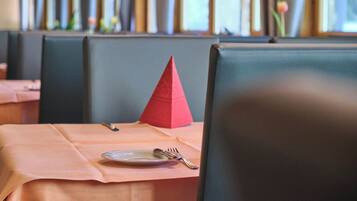 Ein Restaurantambiente mit einem gedecktem Tisch, inklusive Teller, Gabel und Messer.