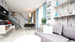Un salon moderne avec un canapé gris, une table basse blanche et un escalier menant à un autre niveau.