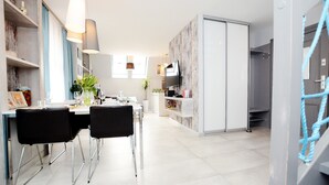 Une cuisine moderne avec un coin repas, un téléviseur fixé au mur et un escalier menant à l’étage supérieur.