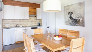 Una cocina moderna con armarios blancos, una mesa de comedor de madera y un cuadro de un ciervo.