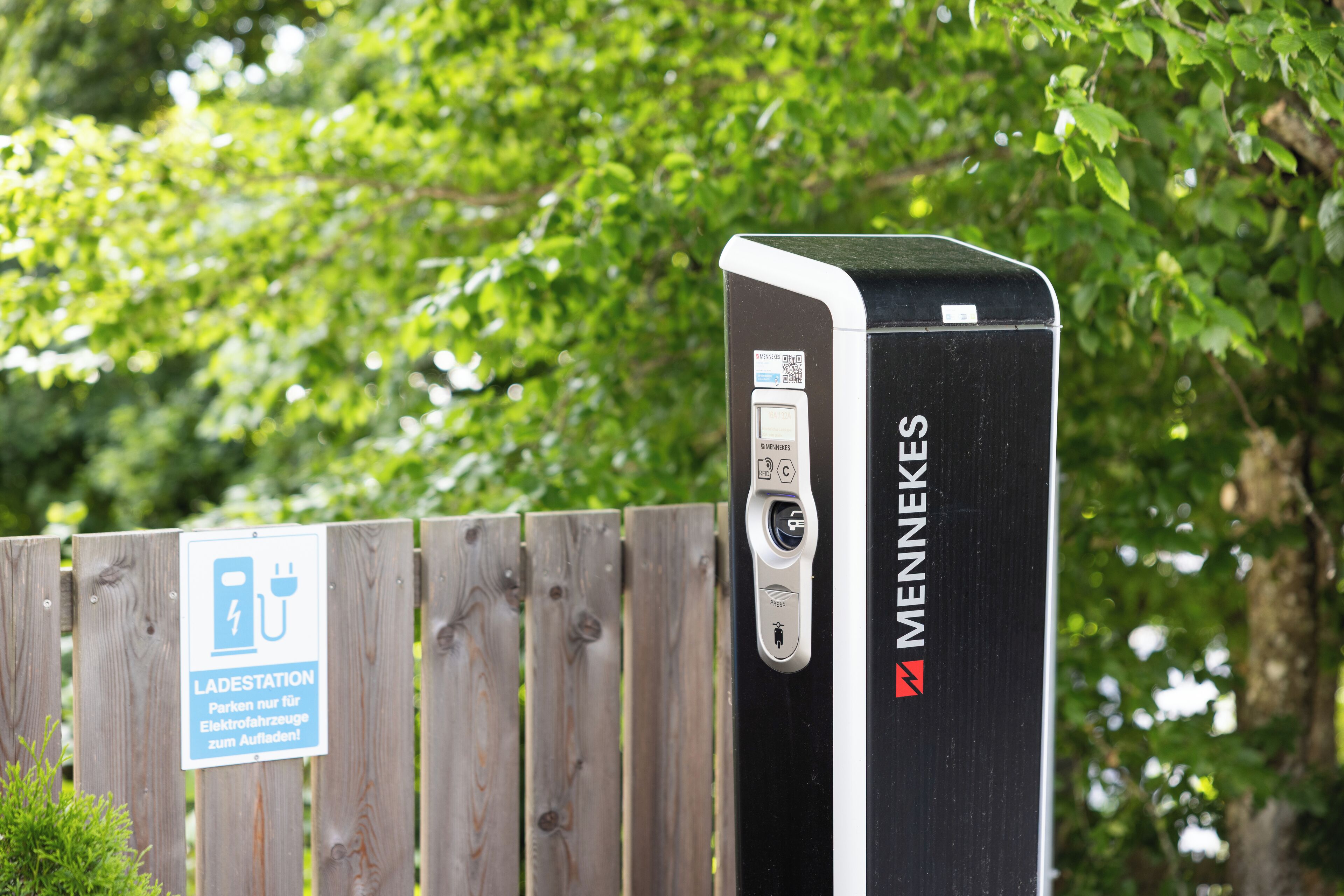A black electric vehicle charging station with a sign indicating it is a Ladestation for electric vehicles.