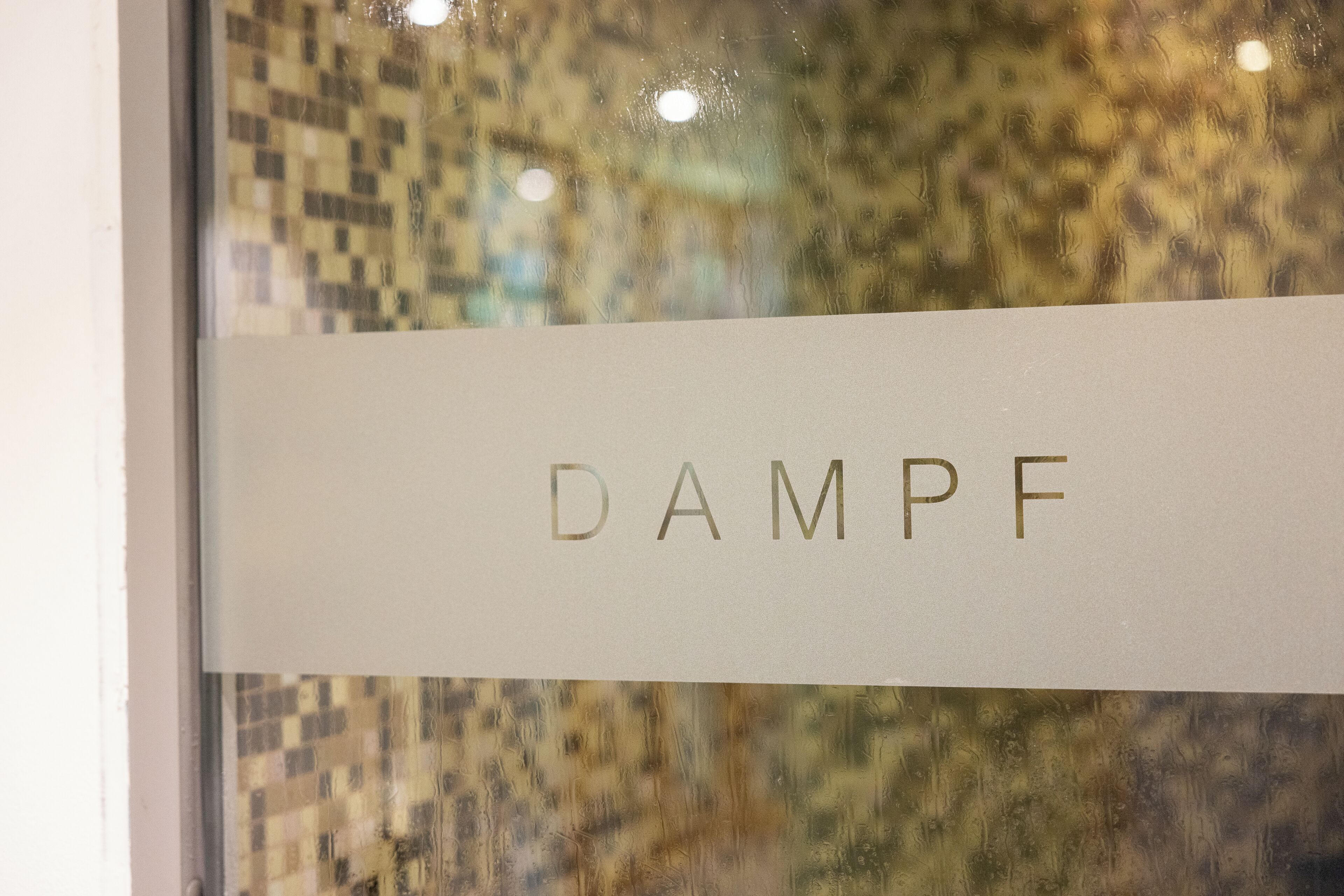 A sign with the text "DAMPF" on a glass window.