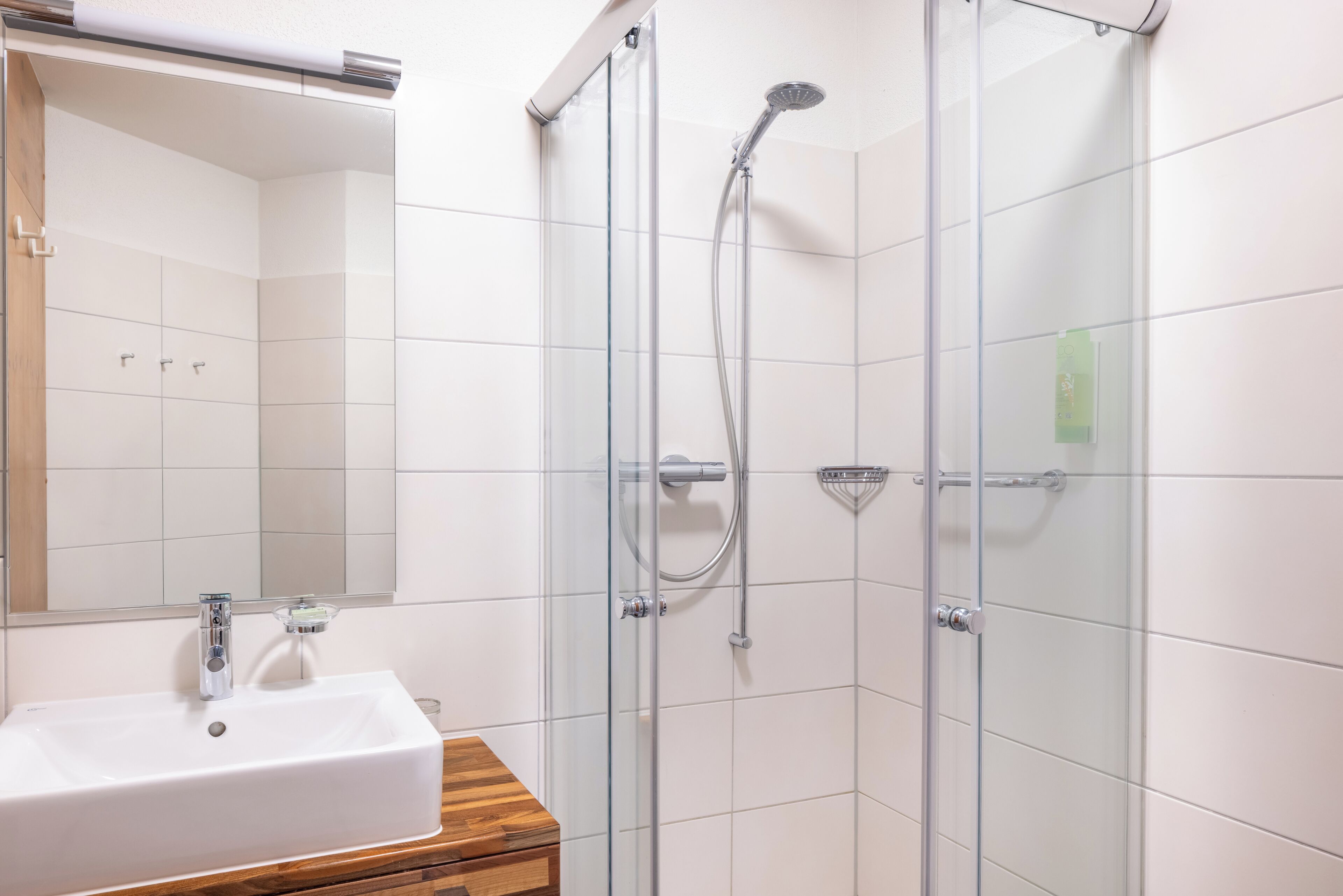A bathroom with a glass-enclosed shower, a white sink, and a wooden vanity.