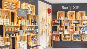 Tienda con cajas de madera y estantes que exhiben diversos productos como miel, huevos y aperitivos.