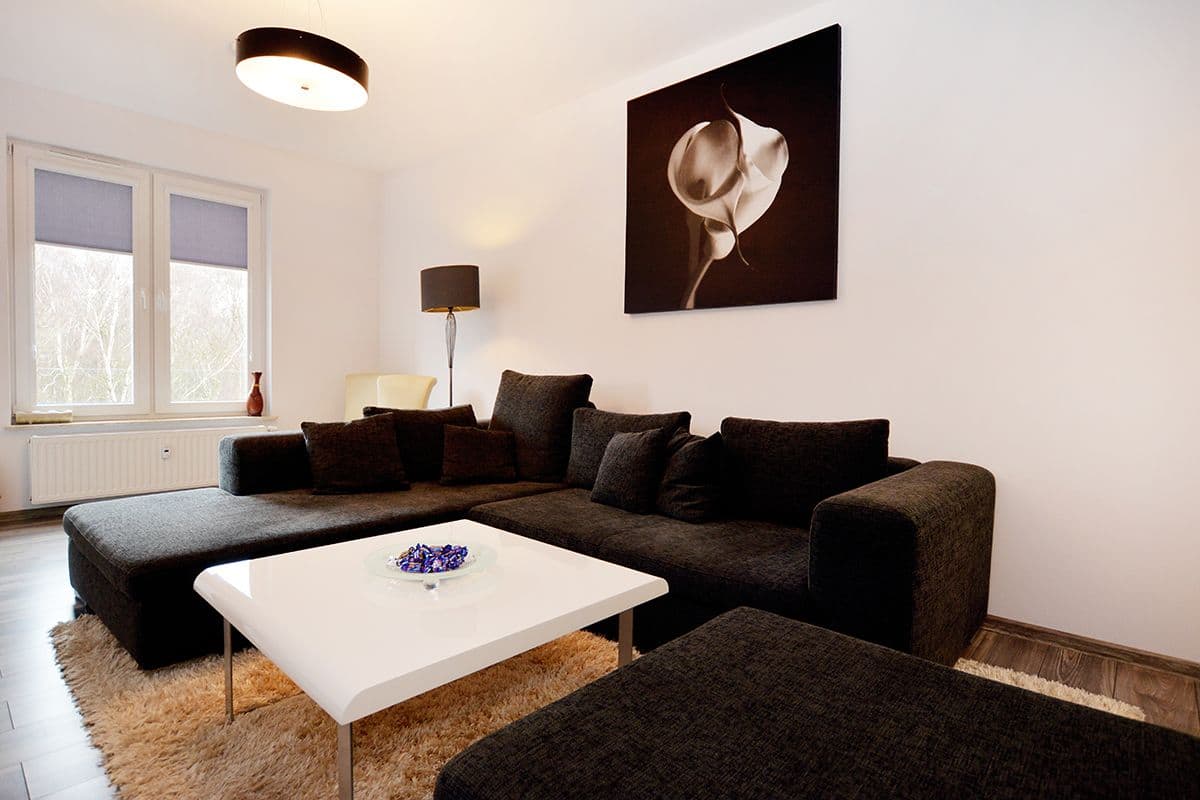 A modern living room with a sectional sofa, a white coffee table, and a large wall-mounted picture.