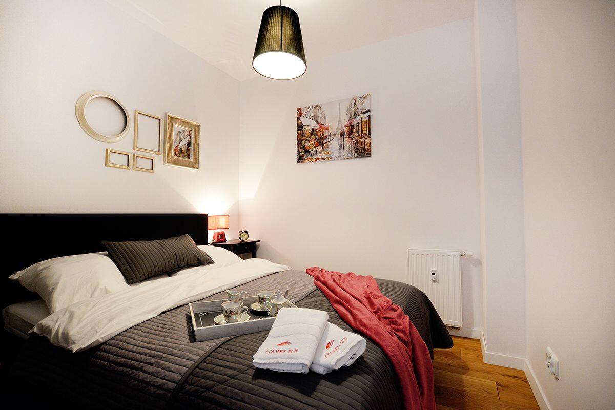 A neatly arranged bedroom with a bed, bedside table, and a wall-mounted picture.