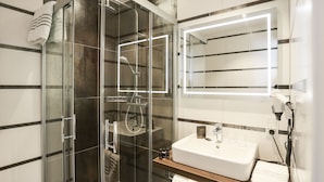 A modern bathroom with a glass-enclosed shower, a white sink with a mirror above it, and a towel rack. - Hotel zur Schloss-Schmiede (Kühbach)