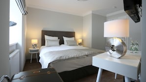 A hotel room with a bed, bedside lamps, a desk with a lamp, and a suitcase. - Hotel zur Schloss-Schmiede (Kühbach)