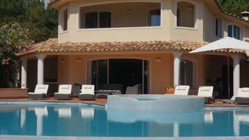 A two-story house with a swimming pool, outdoor seating, and a covered patio area.
