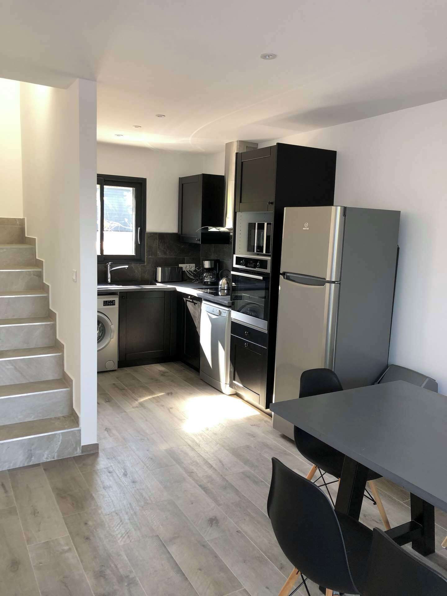 A modern kitchen with a built-in oven, a refrigerator, and a dining area with a table and chairs.