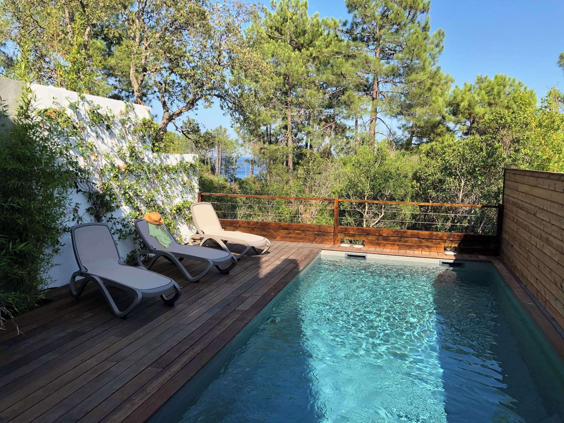Una terrassa de fusta amb una petita piscina i dues gandules.