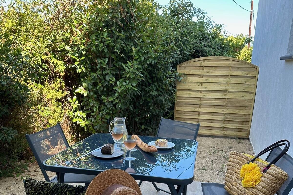 Eine Terrass mit Sitzgelegenheit für zwei Personen, mit einem Korbwägelchen, einem Hut und einem Teller mit Essen.