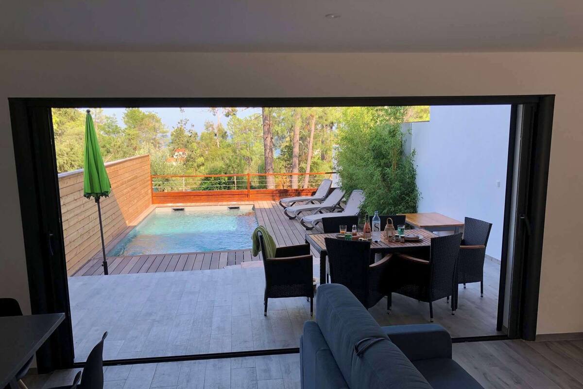 Ein modernes Wohnzimmer mit einem großen Schiebeglasfenster, das auf eine Terrasse im Freien führt.
