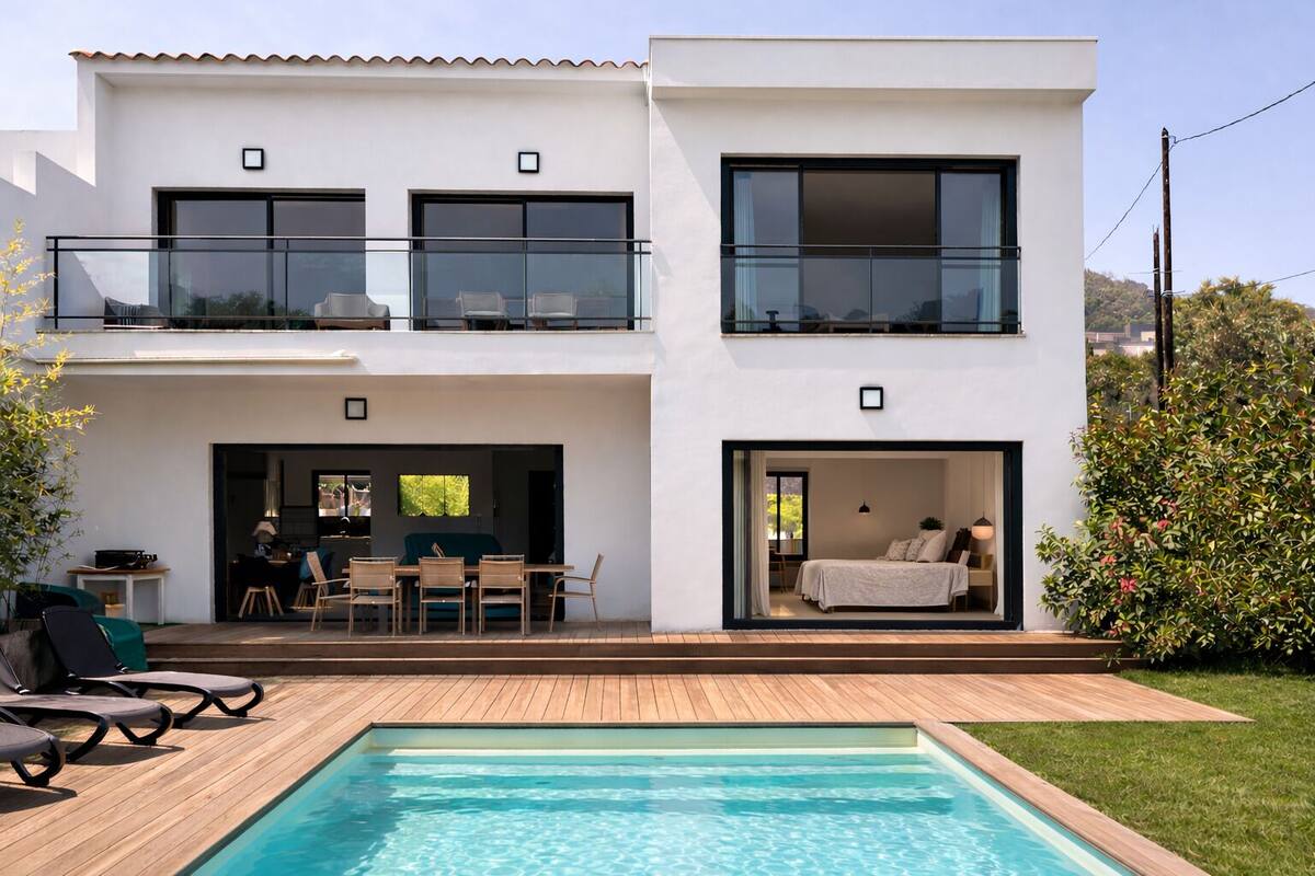 Ein modernes, zweistöckiges Haus mit Swimmingpool, Außenbereich mit Sitzgelegenheit und einem Balkon.