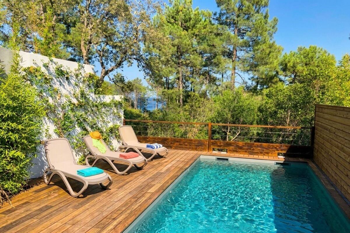 Ein Schwimmbecken mit Holzterrasse und Liegestühlen.