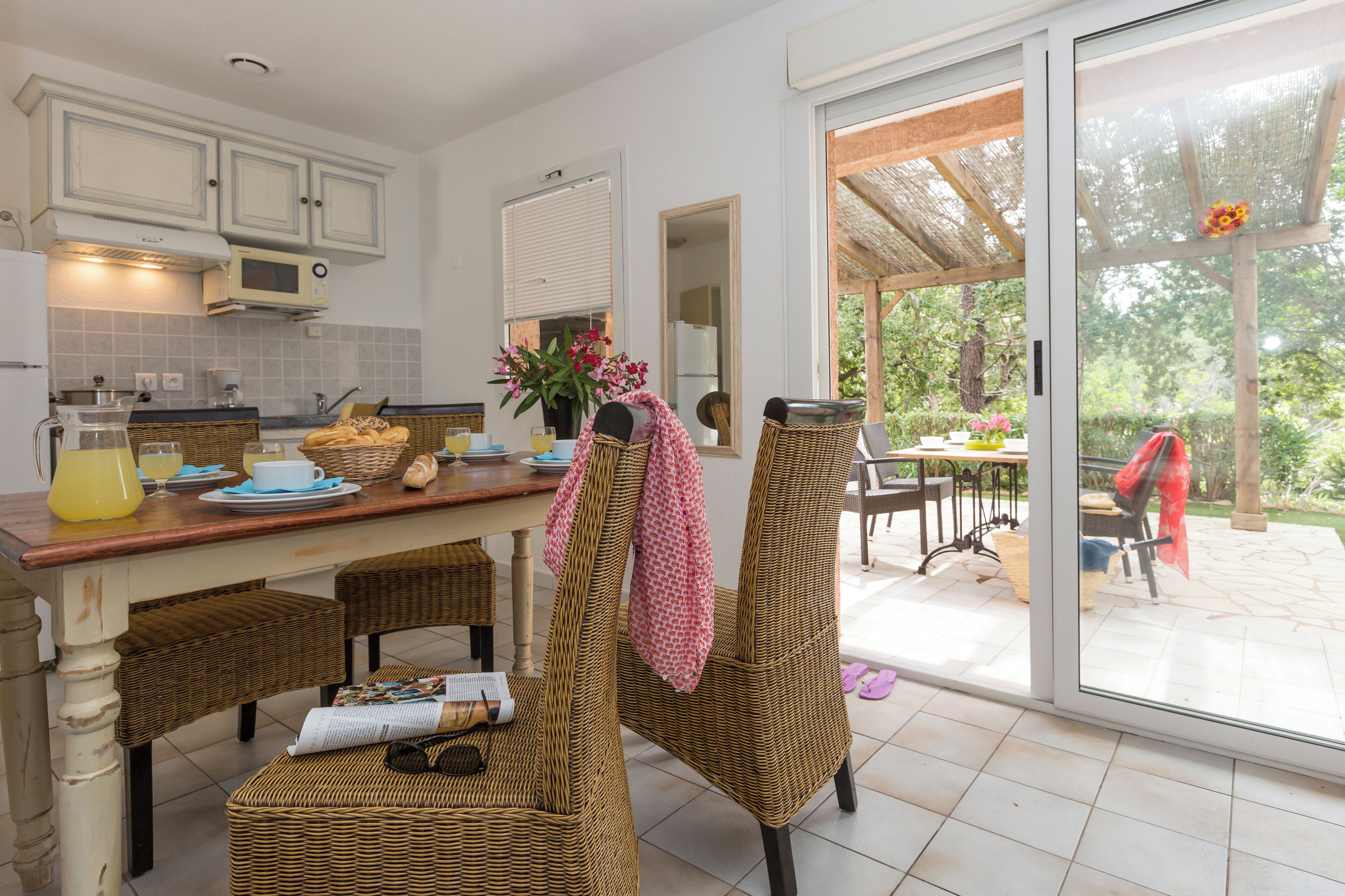A kitchen with wicker chairs, a dining table, and a large sliding glass door leading to an outdoor area.