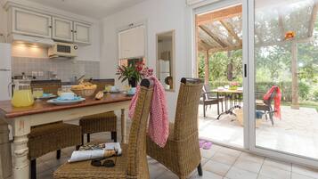 A kitchen with wicker chairs, a dining table, and a large sliding glass door leading to an outdoor area.