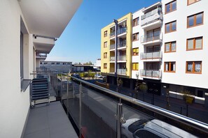 Ein modernes Apartmenthaus mit Balkonen, einem wolkenlosen Himmel und einem Auto auf der Straße.