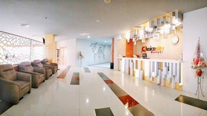 Un espace d’accueil d’hôtel au design moderne, comprenant un comptoir d’accueil, un coin salon et un mur décoratif.