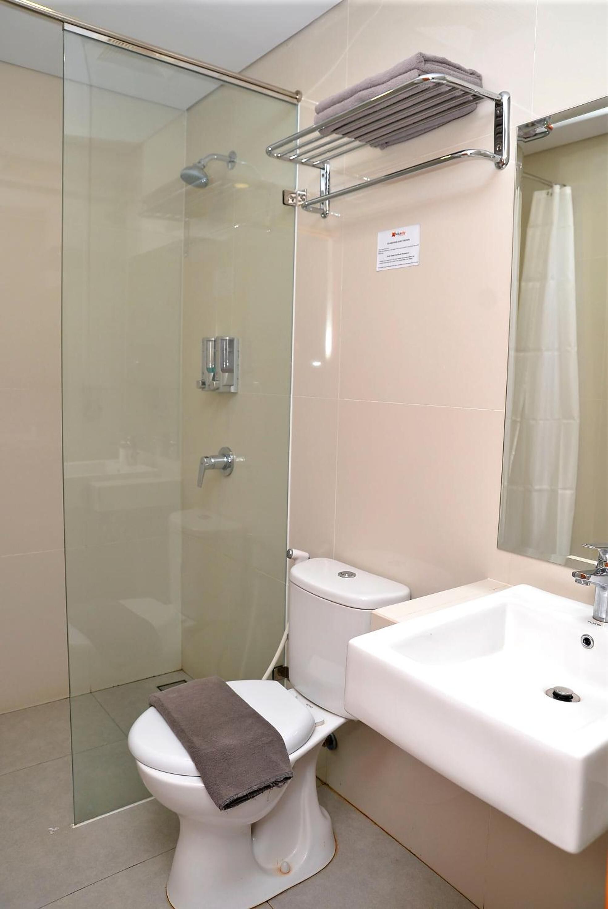 A modern bathroom with a glass shower enclosure, a white toilet, and a sink with a towel rack above it.