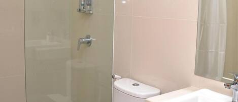 A modern bathroom with a glass shower enclosure, a white toilet, and a sink with a towel rack above it.