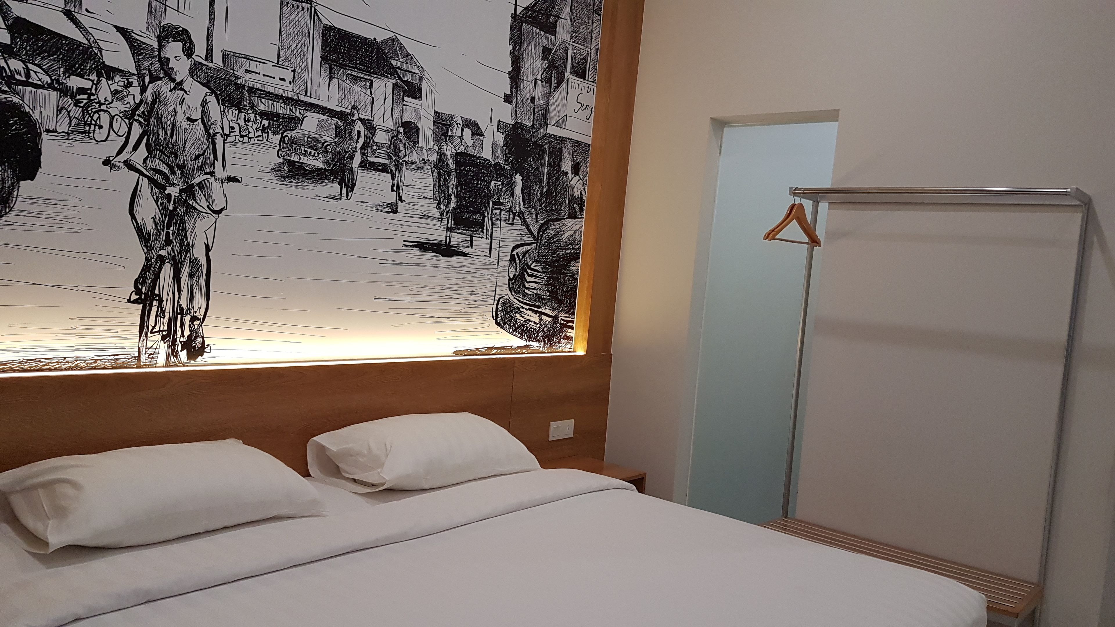A hotel room with a bed, a large black and white mural on the wall, and a wardrobe.