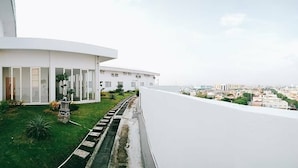Un bâtiment moderne à la façade blanche, doté d’une pelouse bien entretenue et offrant une vue sur le paysage urbain.