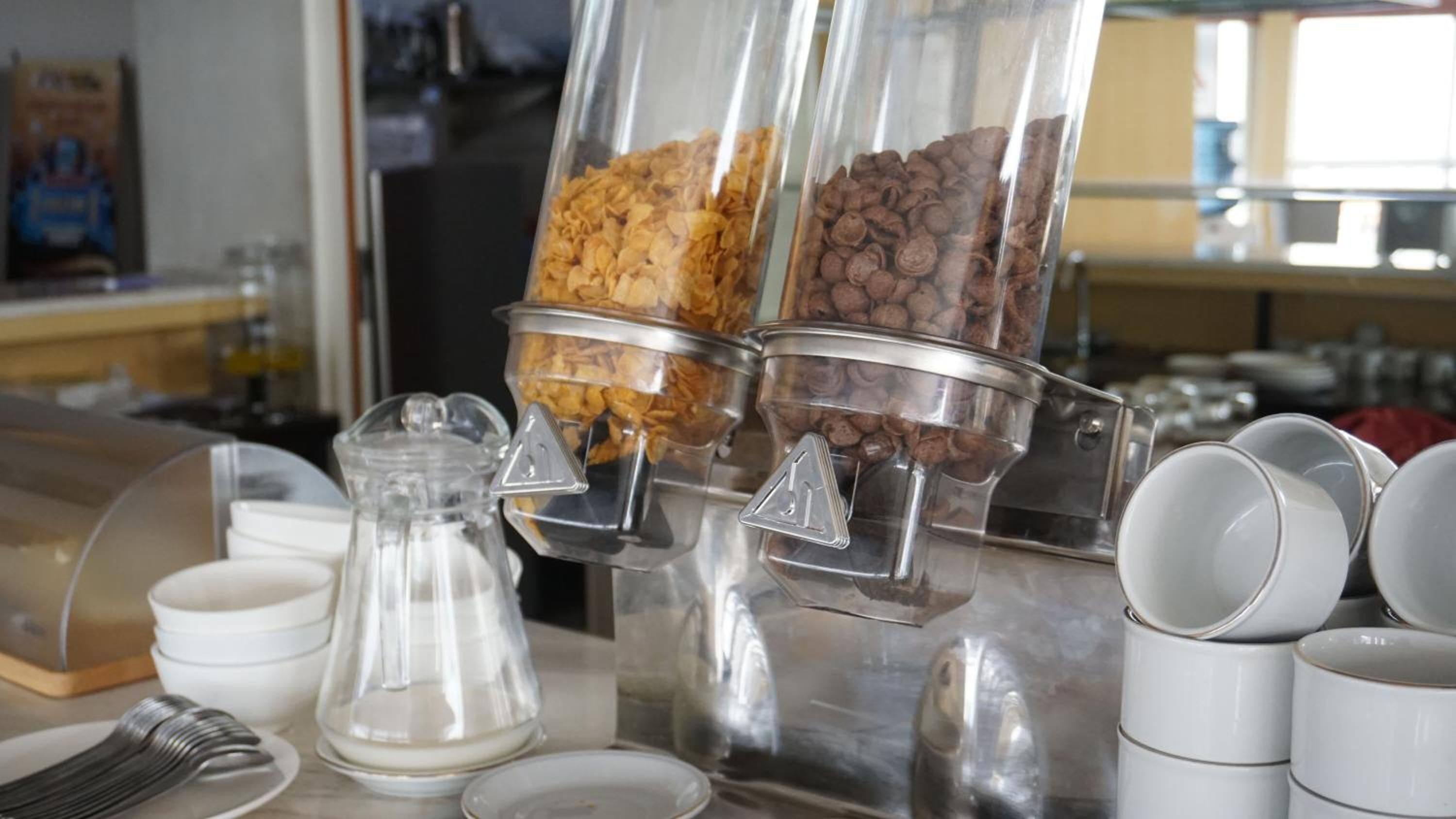 A coffee station with two dispensers filled with coffee beans and cereal flakes.
