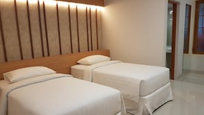 Une chambre d’hôtel avec deux lits, une tête de lit en bois et un luminaire moderne.