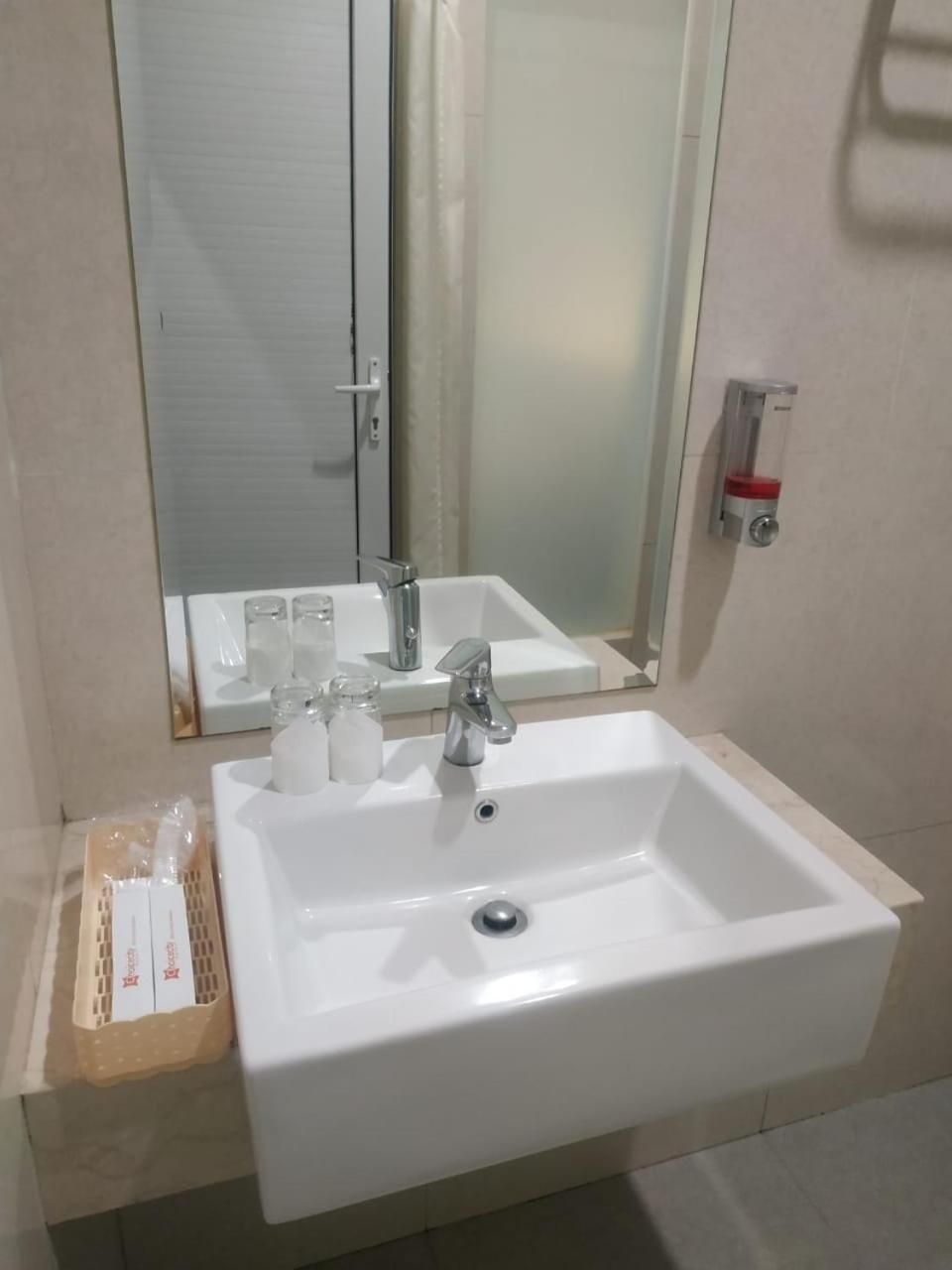 A bathroom with a white sink, a mirror, and a glass shower enclosure.