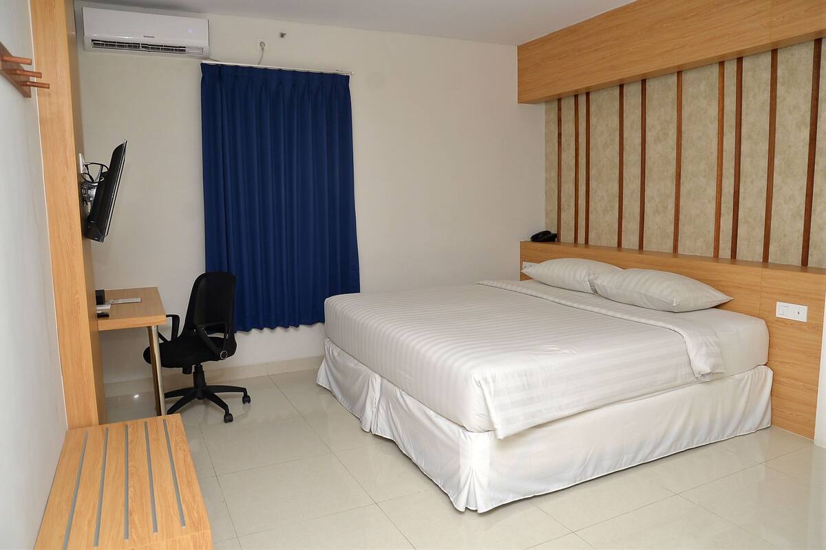 A bedroom with a bed, a desk, a chair, and a curtain.
