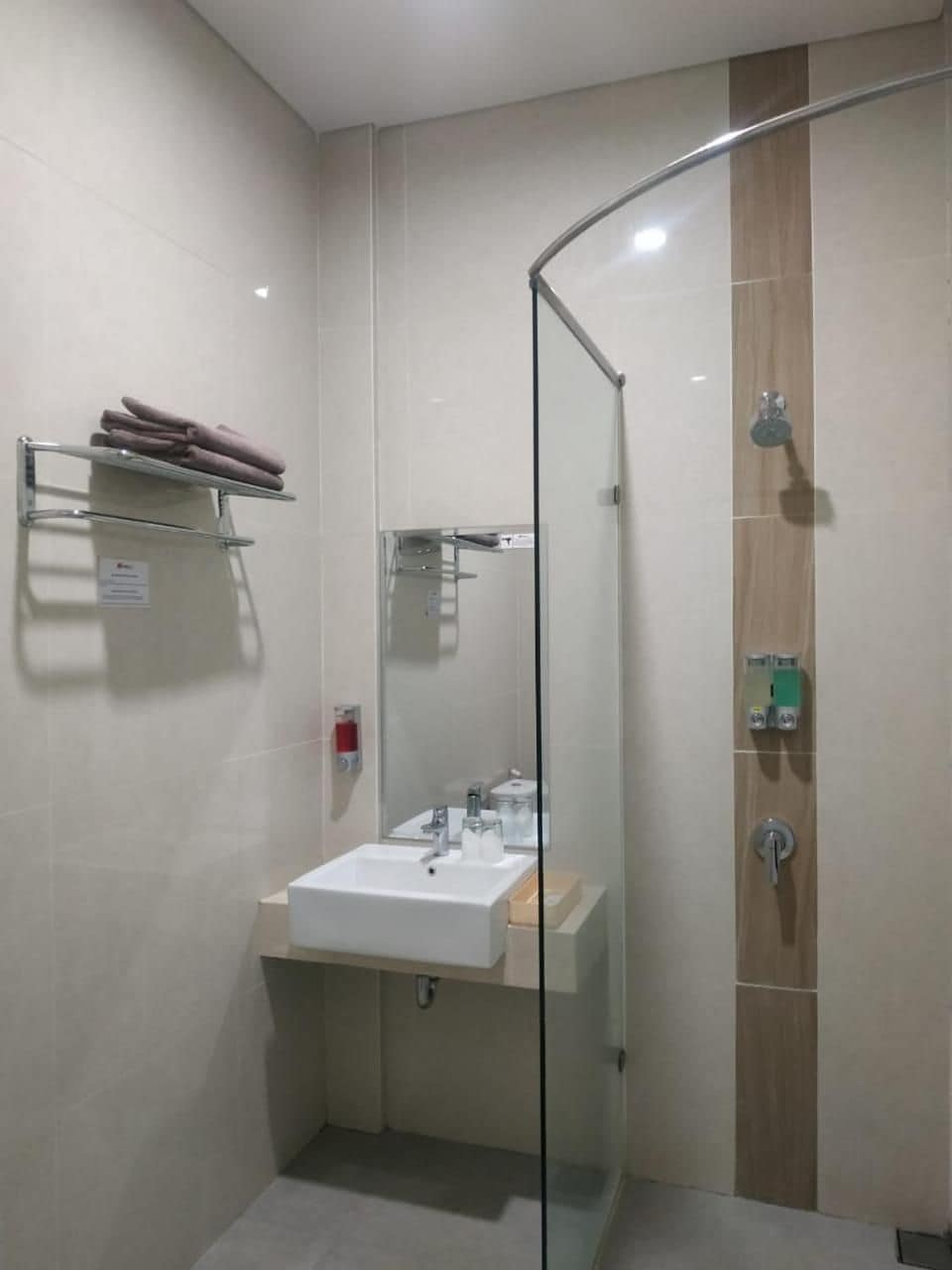 Un baño moderno con cabina de ducha de vidrio, un lavabo con espejo y un perchero para toallas.