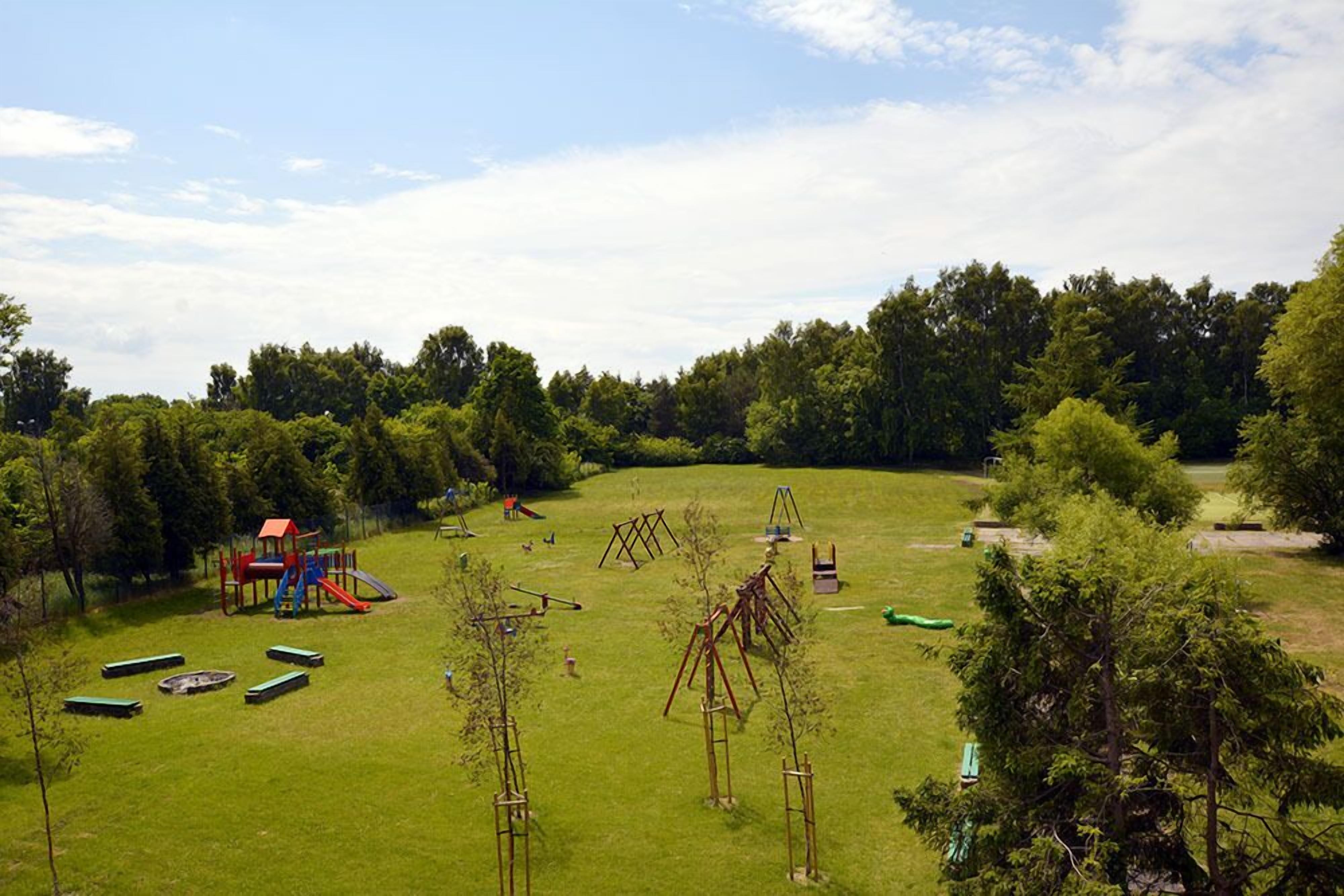 A playground with swings, slides, and climbing structures on a grassy field.