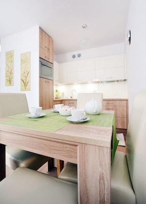 A compact kitchen with white cabinets, a wooden countertop, and a green placemat on the table.