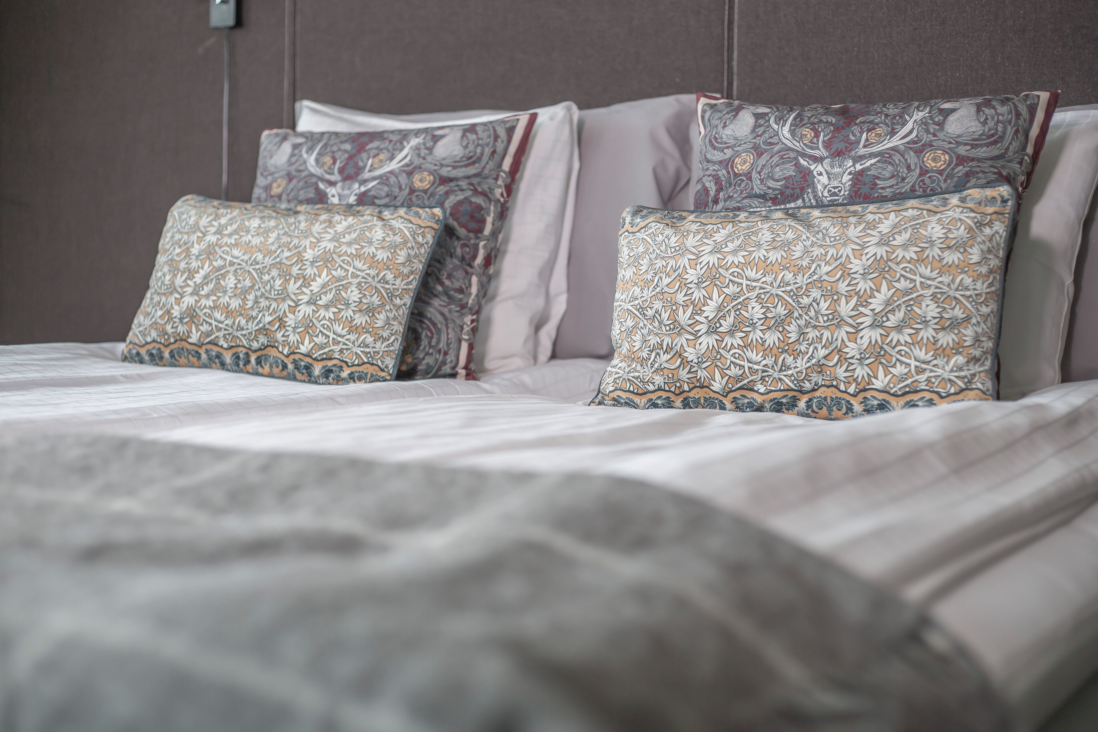 A neatly made bed with patterned pillows and a grey blanket.