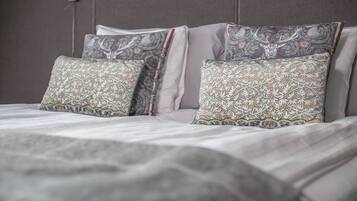 Una cama bien hecha con almohadones estampados y una manta gris.