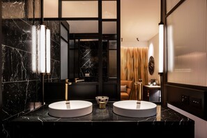 A modern bathroom with two round sinks, a black marble countertop, and a large mirror.