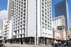 A modern urban building with multiple floors, large windows, and a prominent entrance area.