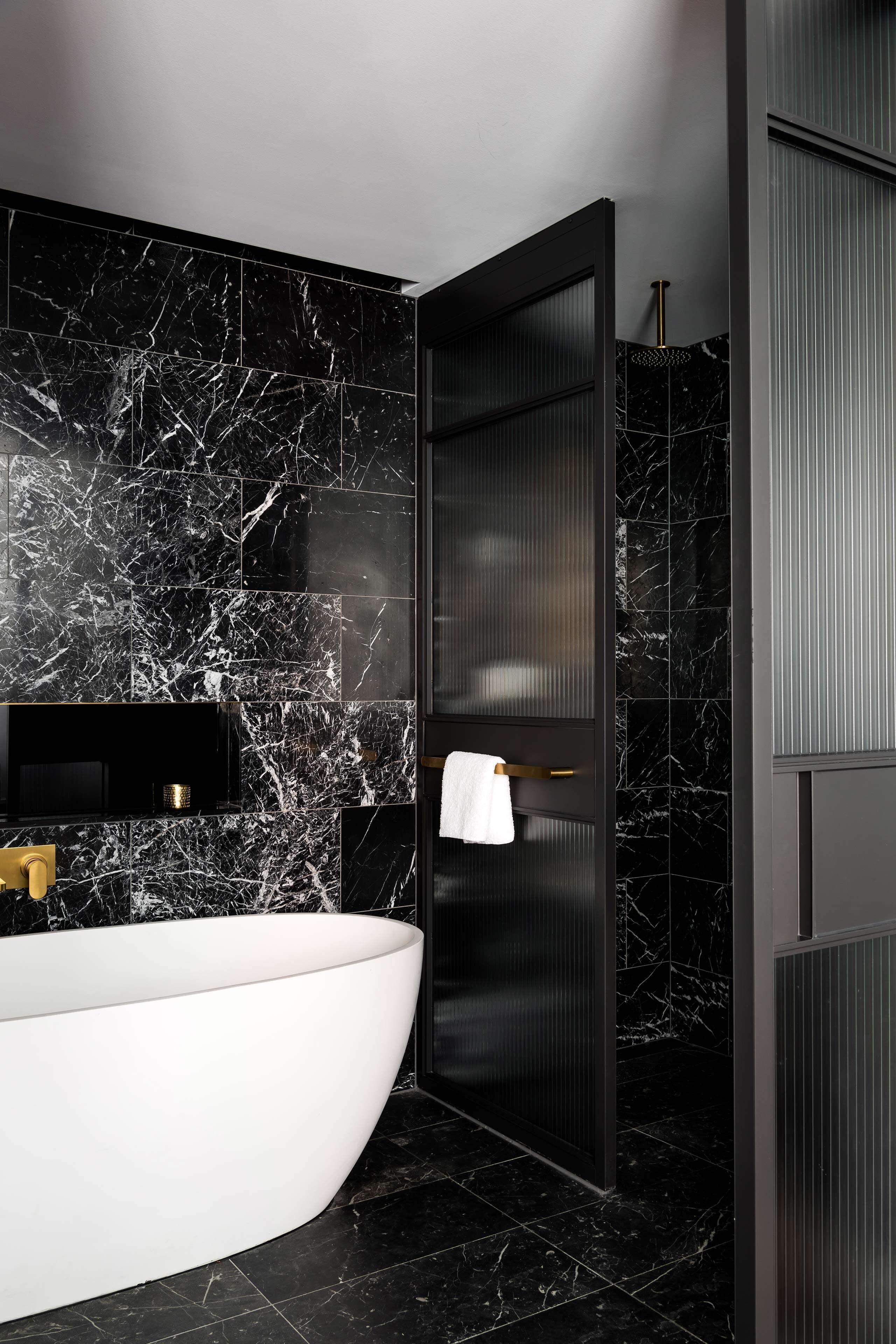 A modern bathroom with a freestanding bathtub, a vanity with a black countertop, and a towel rack.