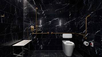 A modern bathroom with black marble tiles, a white toilet, a sink with a gold faucet, and a shower area.