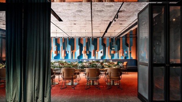 A modern conference room with a red herring floor, wooden chairs, and a blue and orange abstract wall design. - QT Perth (Perth)