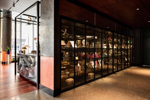 A modern interior with a glass display case filled with various items, a wooden floor, and a large pillar.
