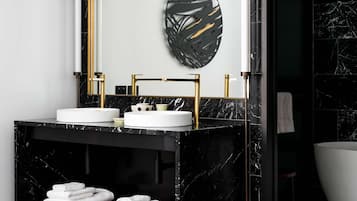 Un baño moderno con tocador de mármol negro, detalles dorados y un espejo grande.