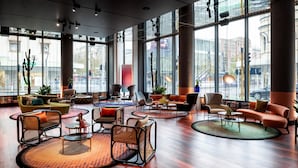 A spacious lobby with modern furniture, large windows, and a view of the city. - QT Perth (Perth)