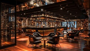 A bar area with multiple seating options, a bartender, and a well-stocked bar counter. - QT Perth (Perth)